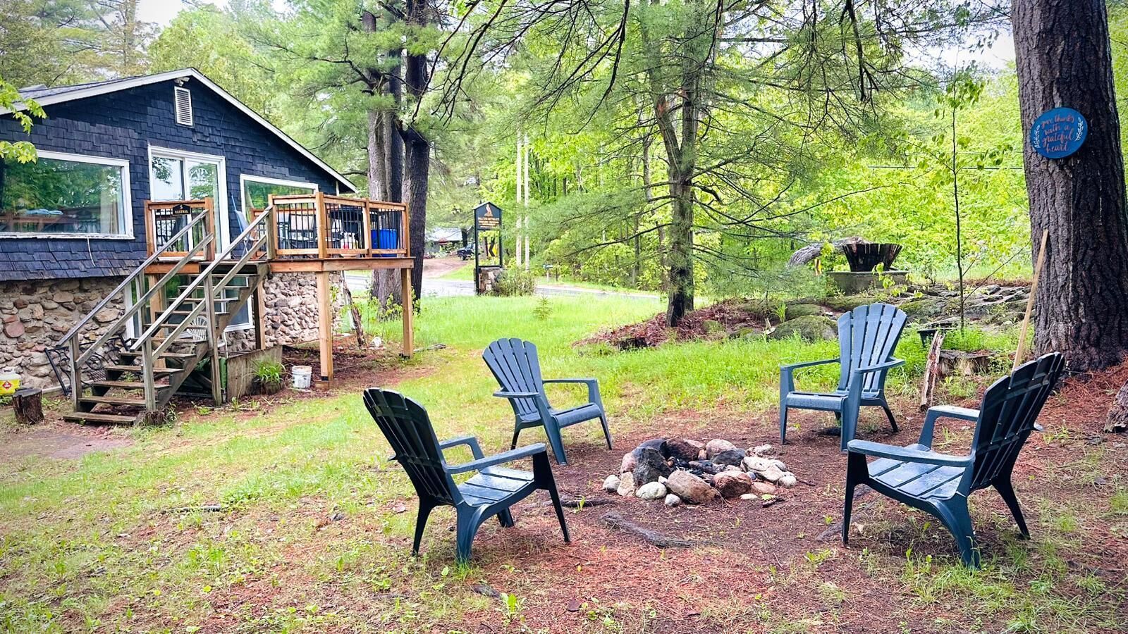A cabin with a deck, outdoor seating, and a fire pit.
