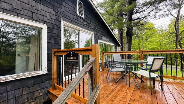 Une terrasse en bois avec des meubles d’extérieur, une boîte aux lettres et une plaque indiquant le numéro de la maison.