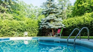 Une piscine avec une échelle en métal et une chaise rouge.
