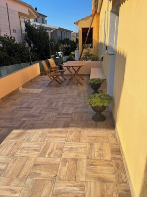 A rooftop terrace with wooden flooring, a table, chairs, and potted plants. - Casa Gabriela: A Peaceful 2BR Gateway | Private Parking, AC, Near Beach (Viddalba)