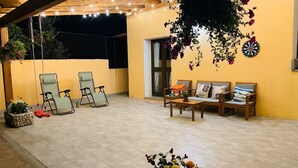 Une terrasse extérieure avec des chaises, une table et des jardinières suspendues.