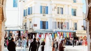 Un arco conduce a una piazza vivace con un edificio storico sullo sfondo.