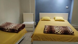 Una stanza con due letti, ognuno con una coperta a stampa leopardo e cuscini gialli. Si nota un comodino bianco e un termosifone sulla parete.
