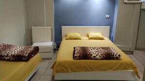 Una stanza con due letti, ognuno con coperta a stampa leopardo e biancheria gialla. Si vede un termosifone bianco e una parete decorata in blu.