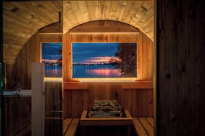 A sauna room with wooden walls and a large window overlooking a body of water at sunset. - Waterfront Resort! Pickleball+Sauna+Pool+Hot Tub (West Palm Beach)