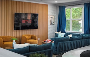 Ein modernes Wohnzimmer mit einem Flachbildfernseher, zwei Sofas, einem Couchtisch und einem Fenster mit Vorhängen.