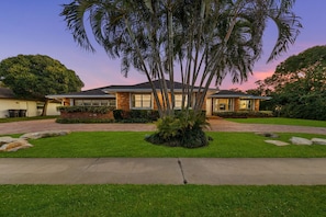 A two-story house with a brick exterior, large windows, and a well-maintained lawn. - Waterfront Resort! Pickleball+Sauna+Pool+Hot Tub (West Palm Beach)