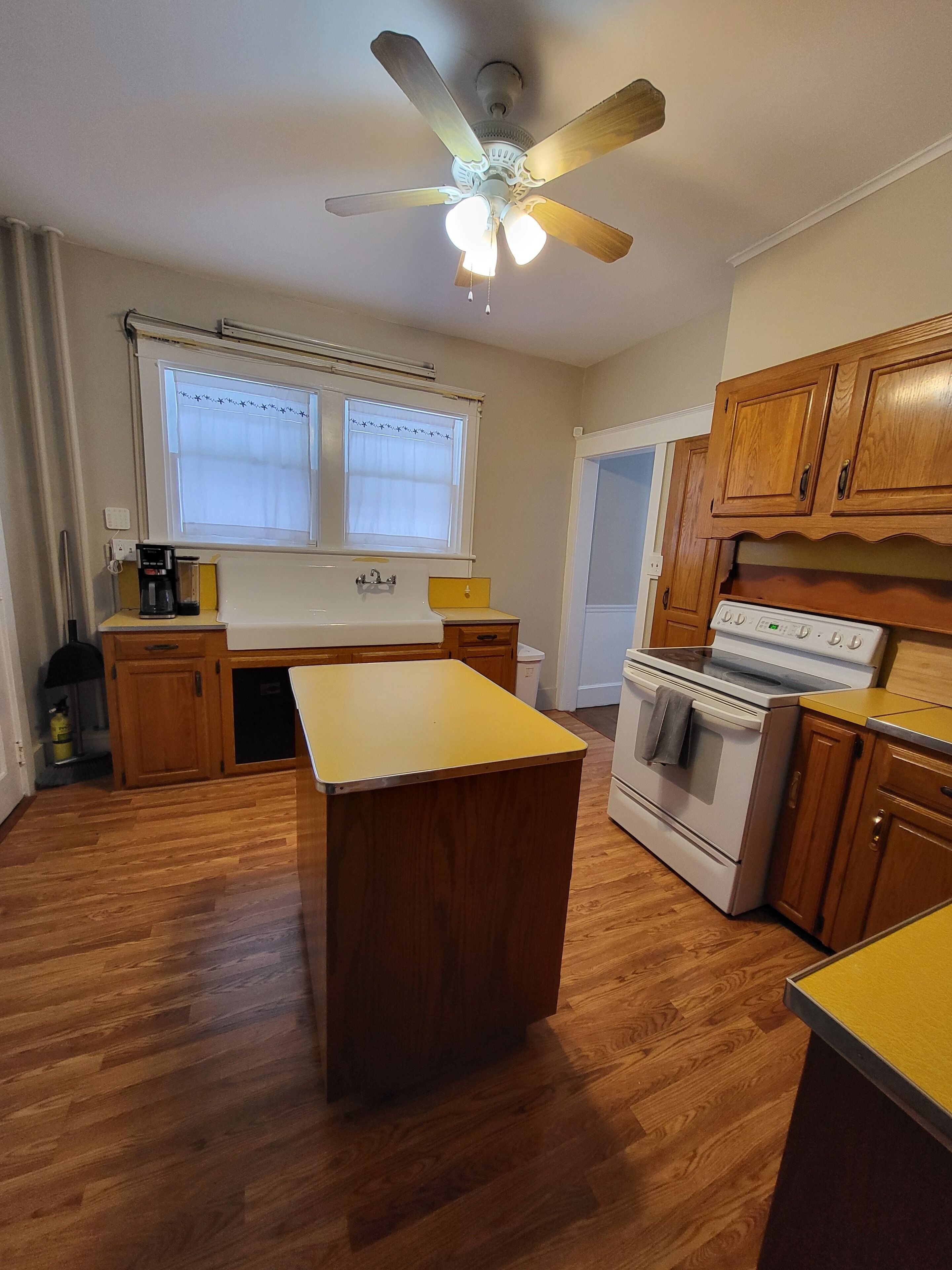 Una cocina con armarios de madera, una isla central, una estufa y un ventilador de techo.