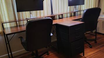 A room with two desks, each with a computer monitor and keyboard, and two office chairs.