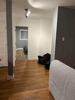 Una habitación con una cama, una puerta, una lámpara en el techo y una ventana con persianas.
