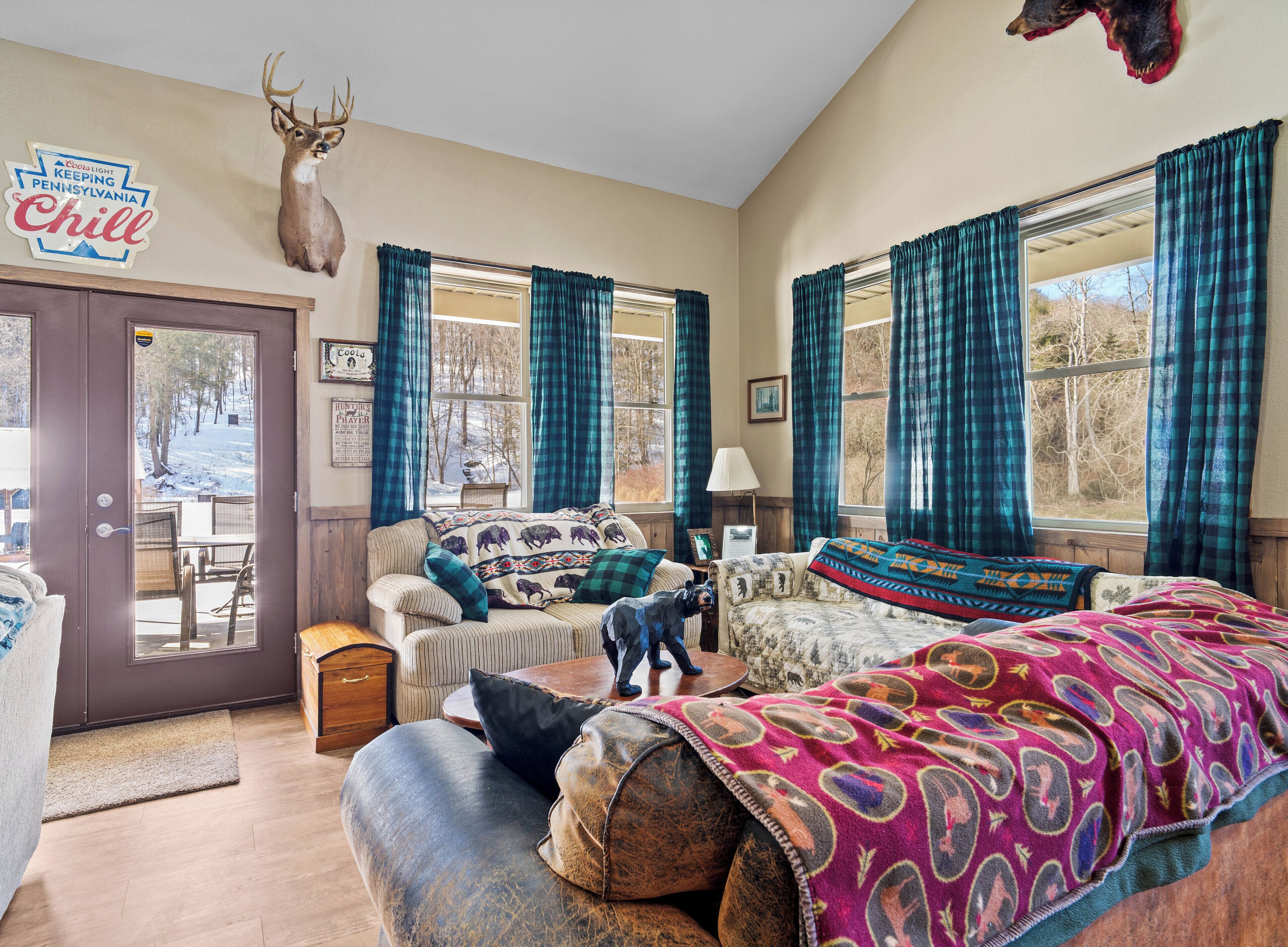 A cozy living room with a fireplace, plaid curtains, and a deer head decoration.