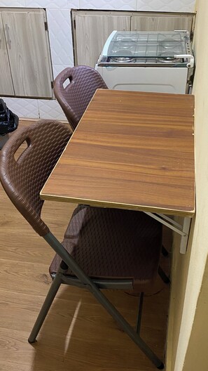 A compact kitchen with a wooden table and two wicker chairs. - Cocody Riviera 3, Splendid studio #04 quiet and peaceful residential area (Abidjan)