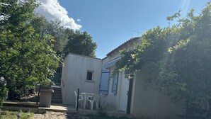 A stone pathway leading to a white building with a blue door, surrounded by greenery and a clear sky. - Cosy and bright gîte with private pool for rent (Bollène)