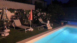 A swimming pool with lounge chairs and an umbrella, surrounded by greenery and a fence. - Cosy and bright gîte with private pool for rent (Bollène)