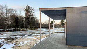 A covered outdoor area with a paved walkway, metal poles, and a building with a grey facade. - Awesome home in Ringkøbing with WiFi (Ringkøbing)