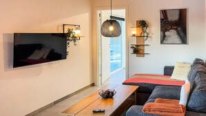 A modern living room with a flat-screen TV mounted on the wall, a wooden coffee table, a gray sofa, and a red throw blanket. - Awesome home in Ringkøbing with WiFi (Ringkøbing)
