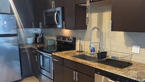 A modern kitchen with dark cabinets, stainless steel appliances, a microwave, stove, oven, and a dishwasher. - Cozy 1-bedroom apartment in beautiful Vienna with AC and gym access (Vienna)