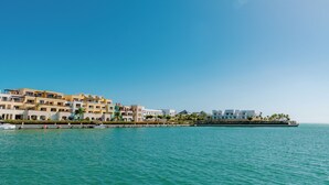 A coastal hotel with multiple buildings, a marina, and a clear blue sky. - TAN Residences at Fishing Lodge (Punta Cana)