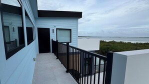 Un balcon donnant sur la plage, un espace couvert avec une fenêtre et une rambarde.