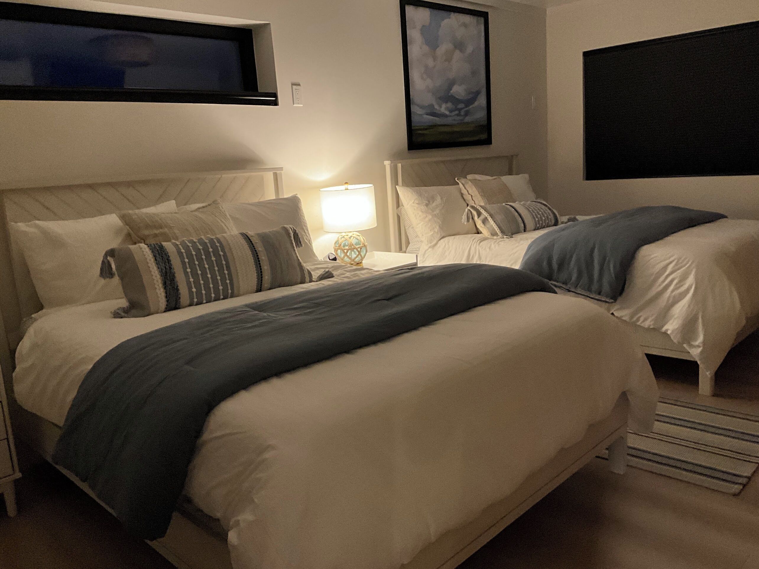 Une chambre d’hôtel avec deux lits, une table de chevet avec une lampe et un tableau au mur.