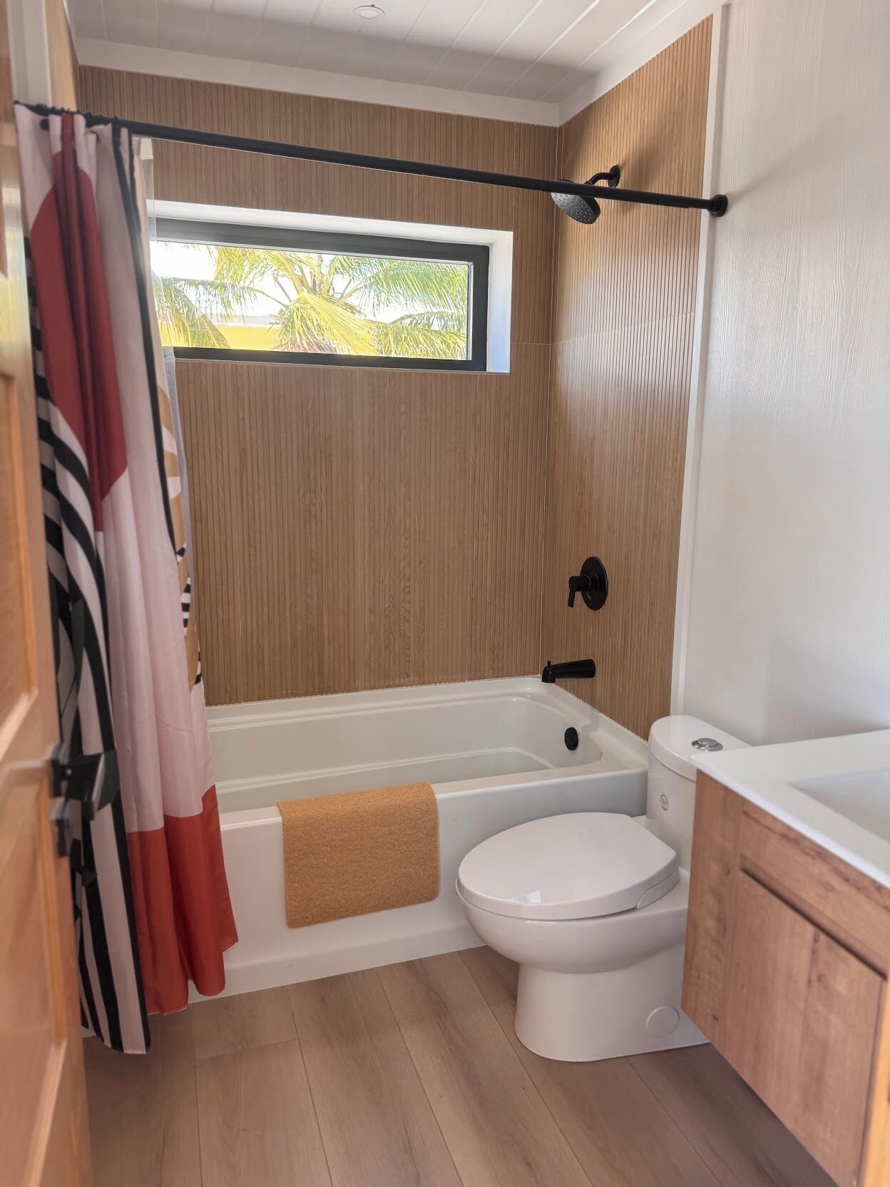 A compact bathroom with a bathtub, toilet, and a window providing natural light.
