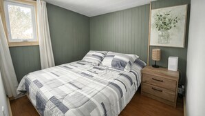 Una camera da letto con un letto, un comodino, una lampada e un quadro appeso al muro.