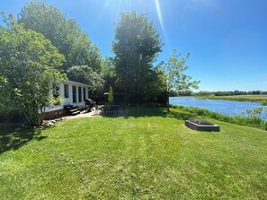 Een huis met terras, barbecue en uitzicht op een meer.