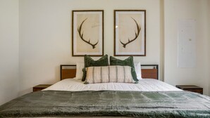 A bed with a green blanket, two framed antler pictures, and a wooden headboard. - RiverandRidge: 3 Min to River, Hot Tub & Fire Pit (Luray)