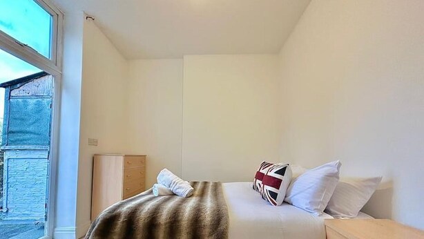 Ein Schlafzimmer mit Bett, Nachttisch, Kommode und Fenster.
