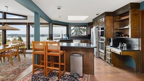 Una cocina moderna con una isla grande, sillas de madera y vistas a un cuerpo de agua.