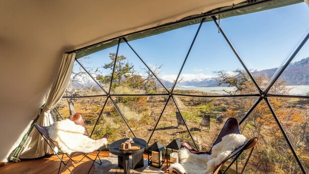 A geodesic dome room with two chairs, a small table, and a view of a mountainous landscape. - Moreno Camp - Glamping with a view (Perito Moreno)