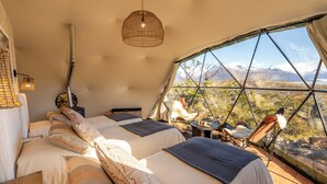 A tented accommodation with three beds, a hanging light fixture, and a view of a mountainous landscape. - Moreno Camp - Glamping with a view (Perito Moreno)