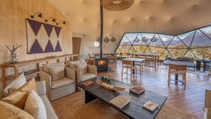 A cozy living area with a fireplace, comfortable seating, and a large window offering a mountain view. - Moreno Camp - Glamping with a view (Perito Moreno)