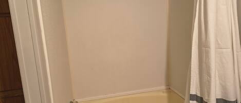 A corner bathroom with a bathtub, a shower curtain, and a wooden door.