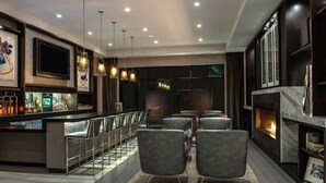 A modern bar area with a fireplace, seating, and a bar counter with a variety of bottles.