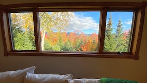 Une pièce dotée d’une fenêtre donnant sur une zone boisée aux couleurs automnales.