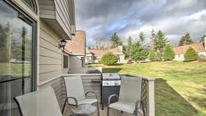 A covered patio with a grill, chairs, and a glass table. - Fv22 Great Location Close to Bretton Woods Ski Area (Bretton Woods)