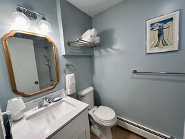 Un baño con lavamanos, espejo, toallero, inodoro y un cuadro enmarcado en la pared.