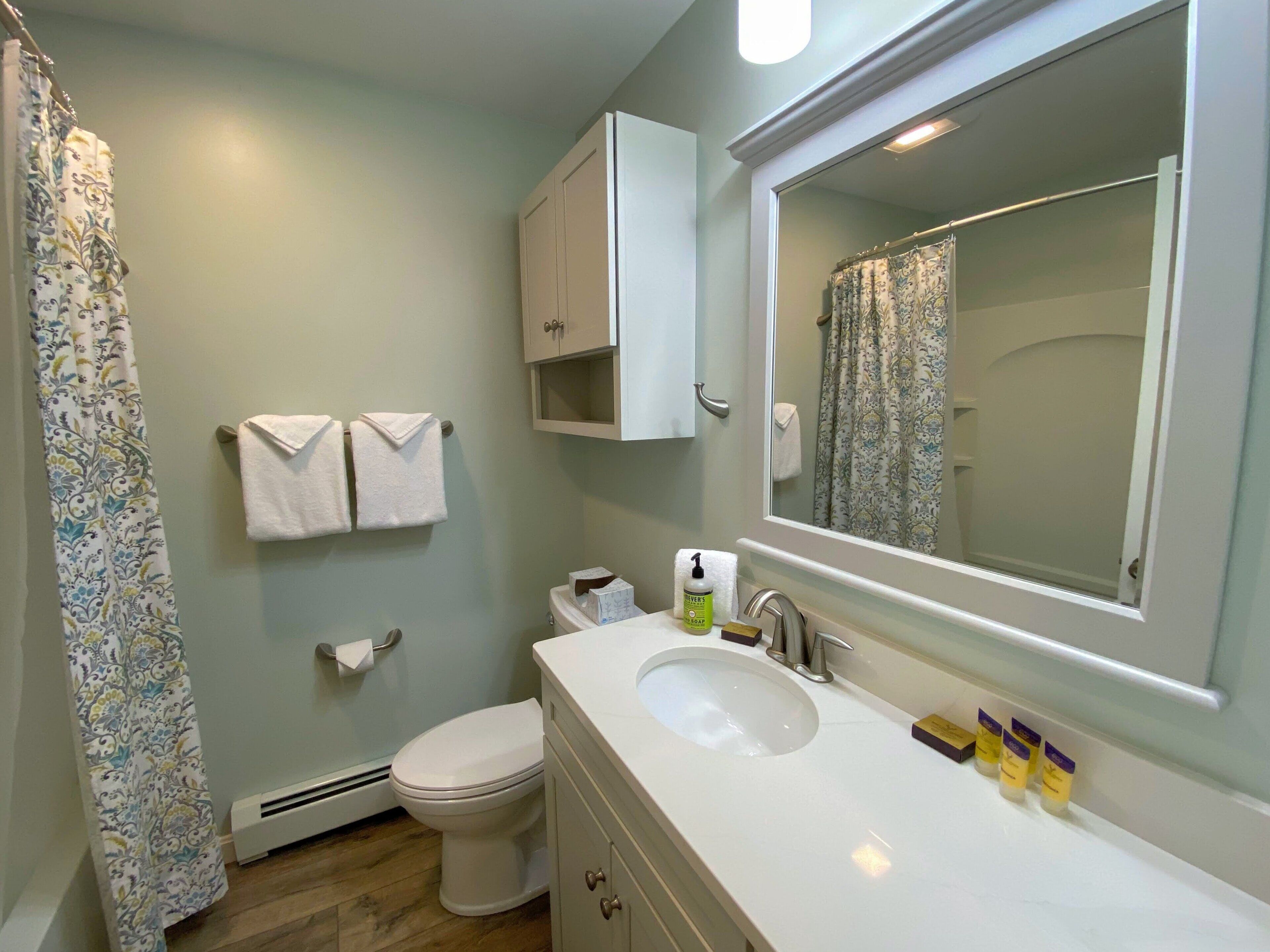Un baño con inodoro, lavabo, espejo y cortina de ducha.