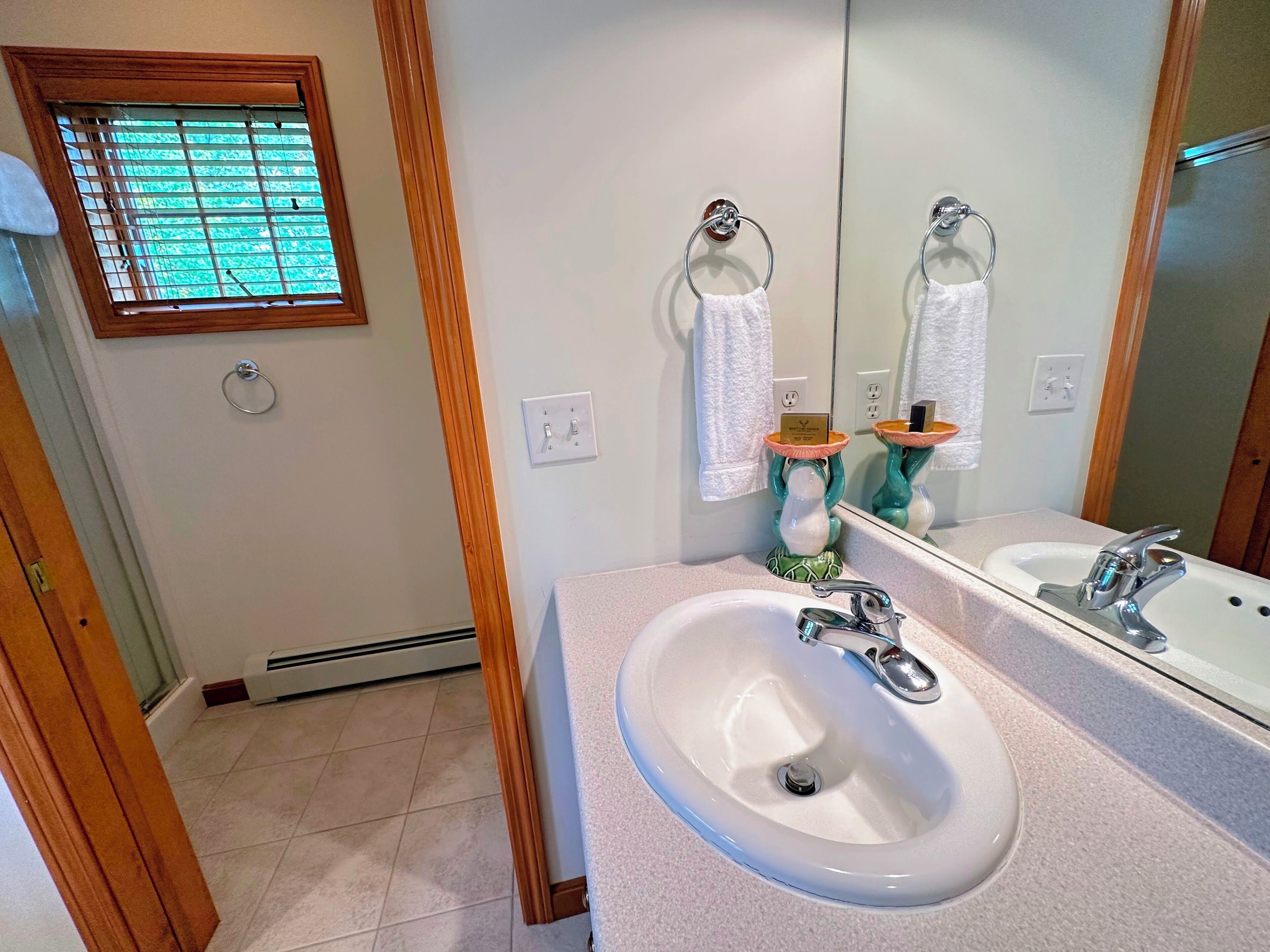 A bathroom with a white sink, a mirror, and a window with blinds.