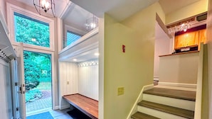 A staircase with wooden steps and a handrail, leading to a landing with a bench and a wall-mounted light fixture. - R21 Completely Renovated Bretton Woods Condo, AC, Unbeatable Ski-in Ski-out Location! Fast Wifi (Bretton Woods)