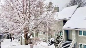 A residential house with a snow-covered roof and a staircase leading to the entrance. - R21 Completely Renovated Bretton Woods Condo, AC, Unbeatable Ski-in Ski-out Location! Fast Wifi (Bretton Woods)