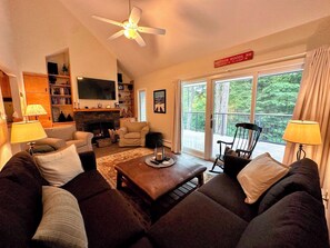 A cozy living room with a fireplace, comfortable seating, and a balcony with a scenic view. - R21 Completely Renovated Bretton Woods Condo, AC, Unbeatable Ski-in Ski-out Location! Fast Wifi (Bretton Woods)