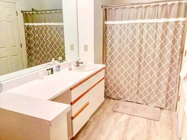 Un baño con lavamanos blanco, espejo y cortina de ducha estampada.