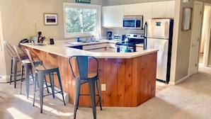 Een moderne keuken met een centraal eiland, barkrukken en uitzicht op de omgeving.