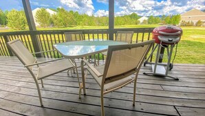A covered outdoor patio with a table and chairs, a barbecue grill, and a view of a grassy yard and trees. - Sc10 Cozy Bretton Woods Ground Level Condo (Bretton Woods)