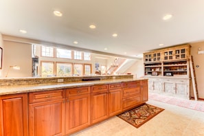A spacious kitchen with wooden cabinets, granite countertops, and a large island. There is a staircase leading to an upper level, and a decorative cabinet with glass doors. - SH4 Bretton Woods Condo With Hot Tub, Next to Skiing and Mt Washington Hotel, ski Slopes Views! (Bretton Woods)