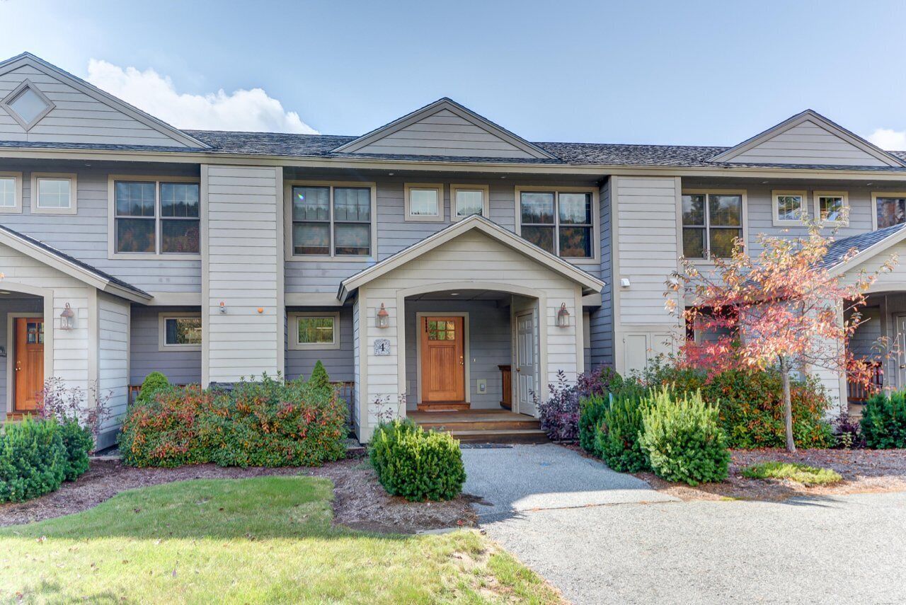A two-story house with a front porch, multiple windows, and a well-maintained garden.