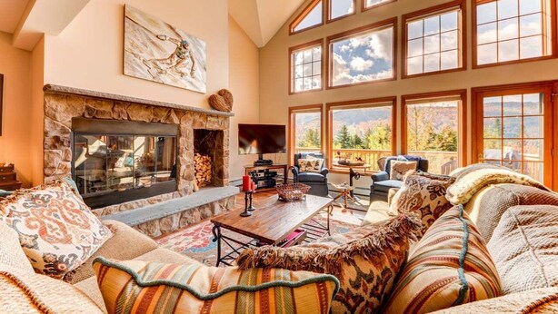 A cozy living room with a stone fireplace, large windows, and comfortable seating. - SH4 Bretton Woods Condo With Hot Tub, Next to Skiing and Mt Washington Hotel, ski Slopes Views! (Bretton Woods)
