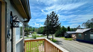 A wooden deck with a view of a road, trees, and a mountain in the background. - Bmv6 Tiny Home Topline (Twin Mountain)